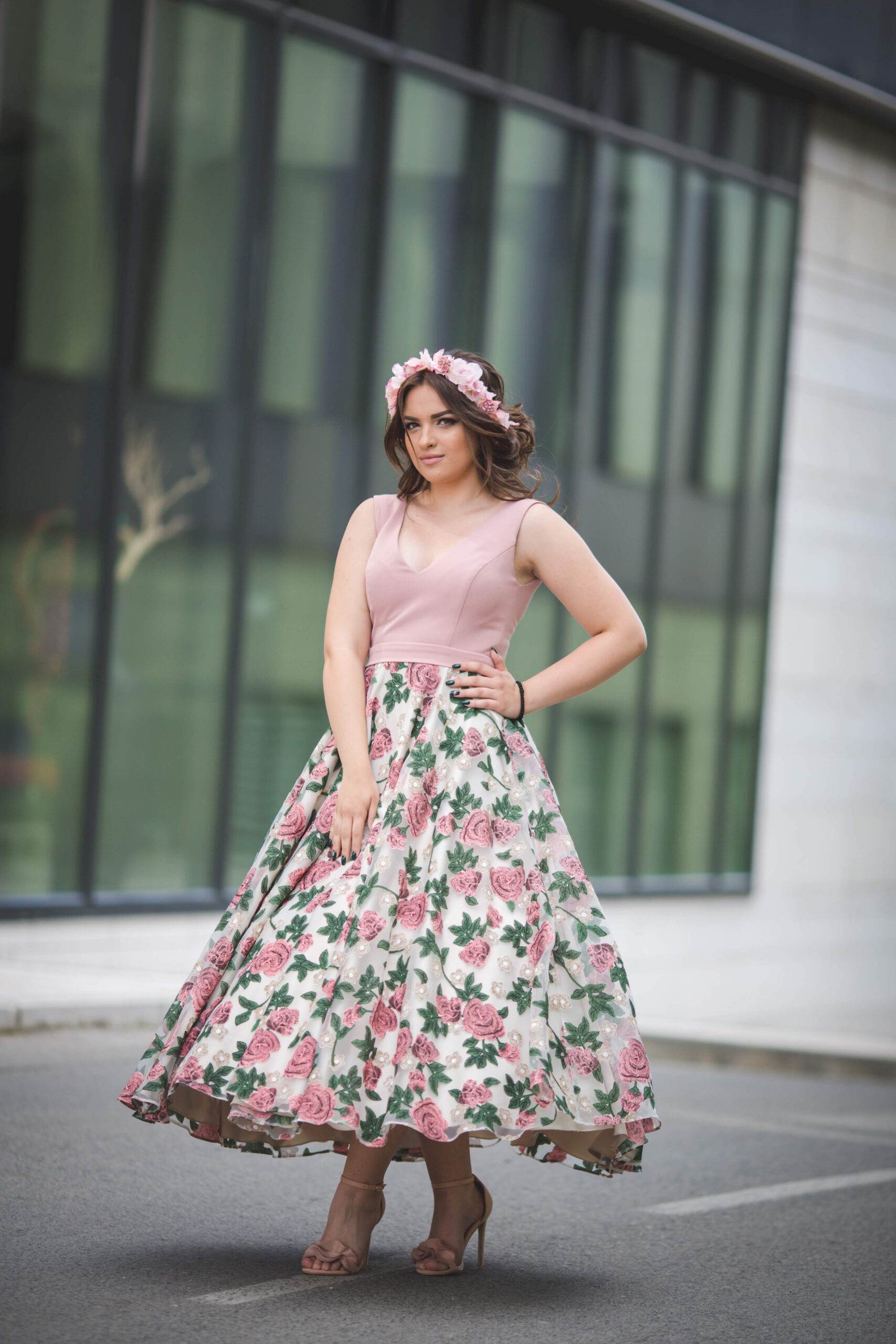 Caucasian standing in front of a modern building in a pink dress and hairband